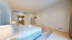 Et moderne hotelværelse med en stor seng, et sengebord, en lampe, et spejl og udsigt til gangen.