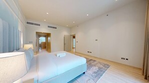 A modern hotel room with a large bed, a bedside table, a lamp, a mirror, and a view of the hallway. - Aesthetic Four-Level 4 Bedroom l near Marina Walk (Dubai Marina)