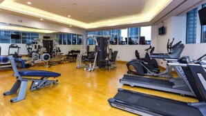Et fitnesscenter med løbebånd, styrkemaskiner og et spejl.