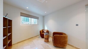 A modern room with a large window, two brown armchairs, a wooden sideboard, and a small table with books. - Aesthetic Four-Level 4 Bedroom l near Marina Walk (Dubai Marina)