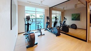 Ein Fitnessstudio mit Trainingsgeräten, großen Fenstern und einem Spiegel.