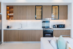A modern kitchen with wooden cabinets, a built-in oven, a microwave, and a coffee maker. - Contemporary 2 Bed in Creek l Free WiFi & Pool (Creek Harbour)