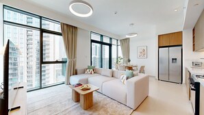 Ein modernes Wohnzimmer mit einer Eckcouch, einem Couchtisch und einer Küchenzeile mit Kühlschrank und Herd.