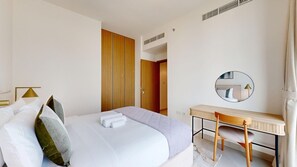A hotel room with a bed, a desk, a mirror, and a door leading to another room. - Contemporary 2 Bed in Creek l Free WiFi & Pool (Creek Harbour)