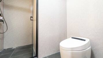 A modern bathroom with a glass shower enclosure, a toilet, and a sink.