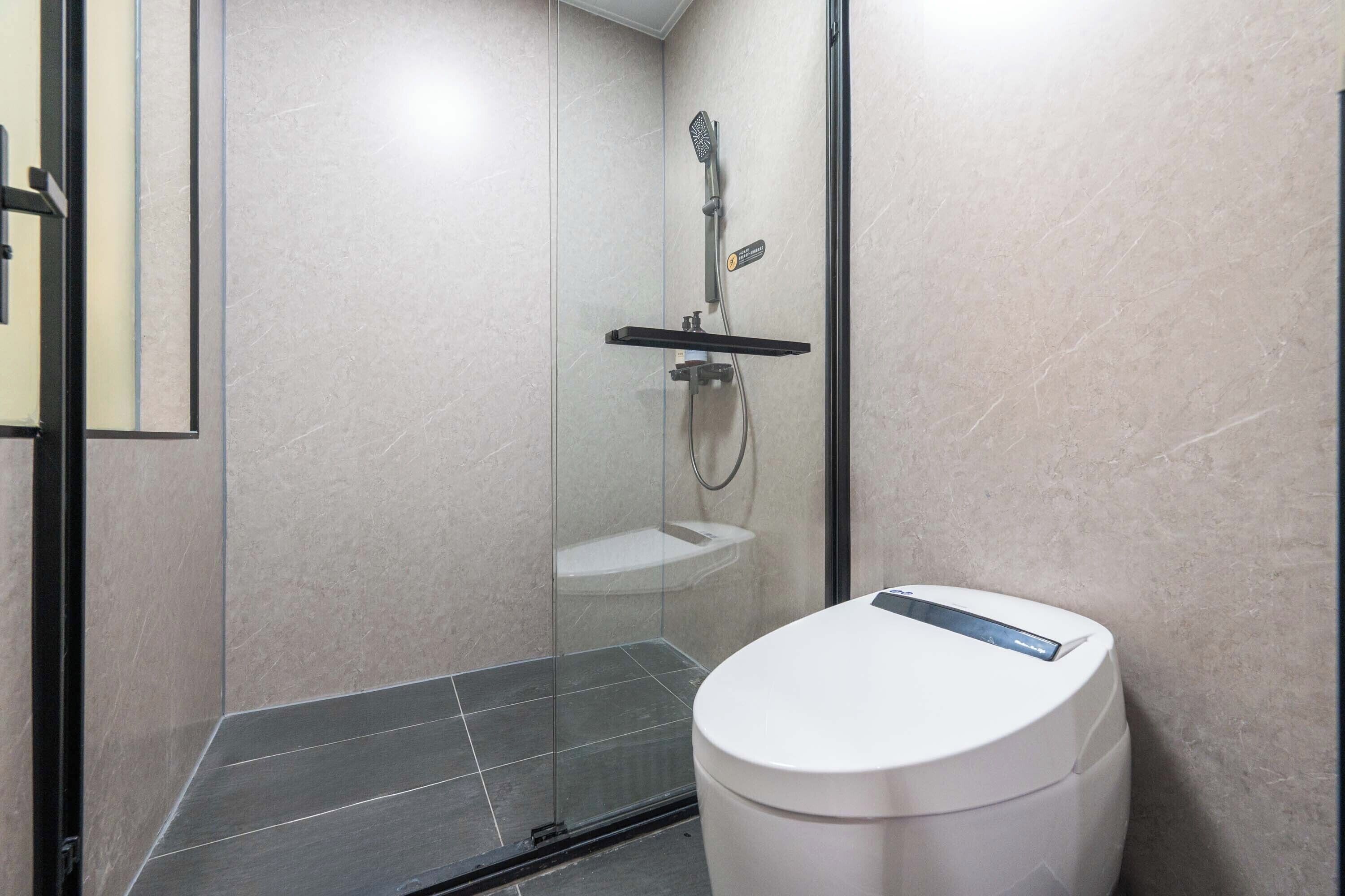 A modern bathroom with a glass-enclosed shower, a white toilet, and a tiled floor.