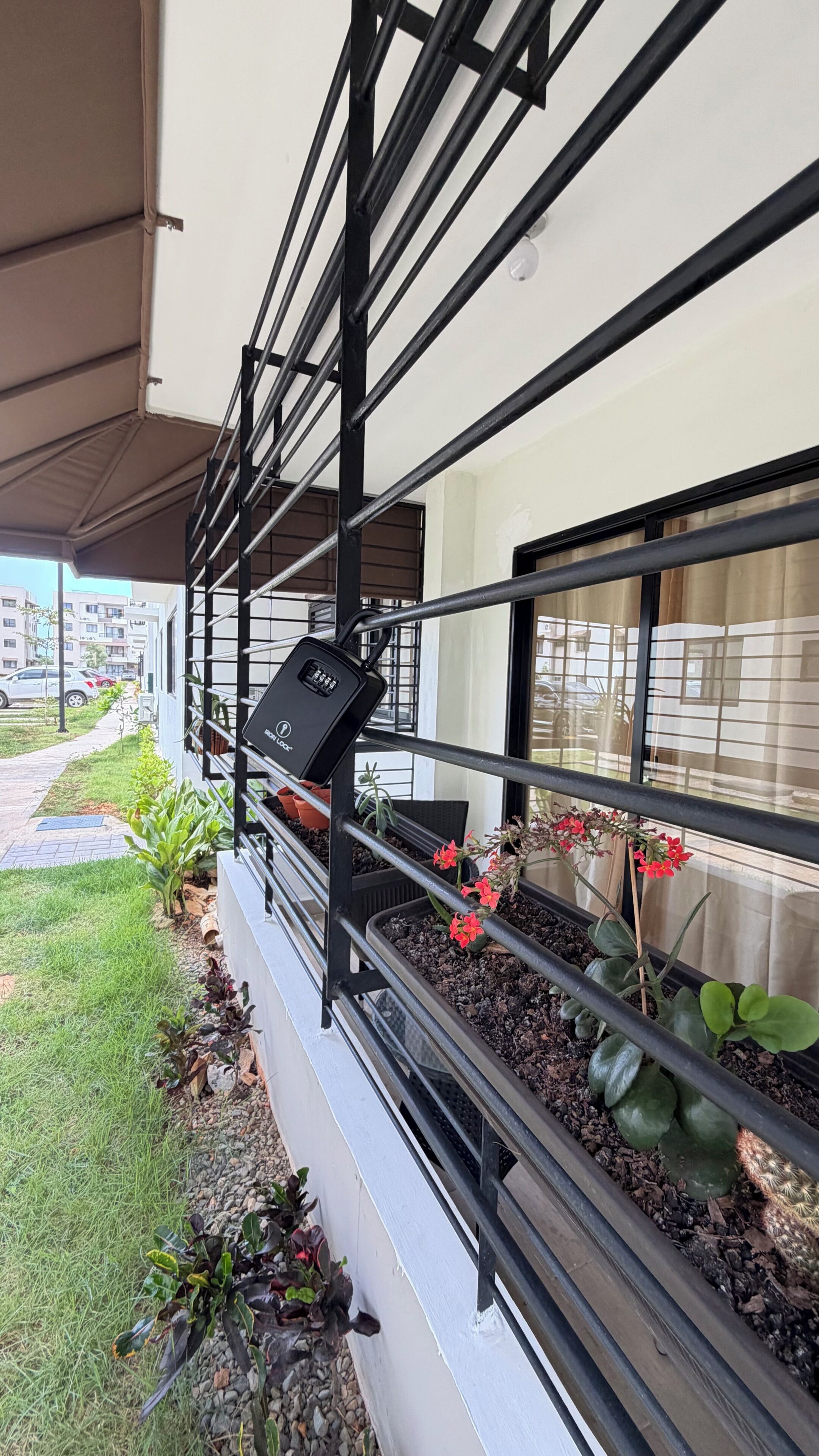 Un balcon avec une balustrade en métal, des plantes en pot et une enseigne.