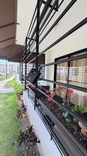 Ein Balkon mit Metallgeländer, Blumentöpfen und einem Schild.
