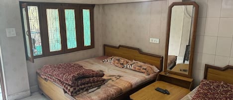 A bedroom with a bed, a bedside table, a mirror, and a window with bars.