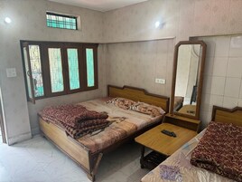 A bedroom with a bed, a bedside table, a mirror, and a window with bars.
