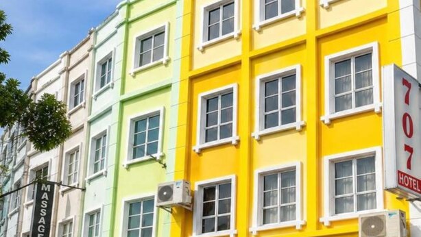 A multi-story building with a prominent yellow facade, a sign for '707 HOTEL MELAKA,' and a massage service sign. - Hotel Taming Sari 707 (Malacca City)