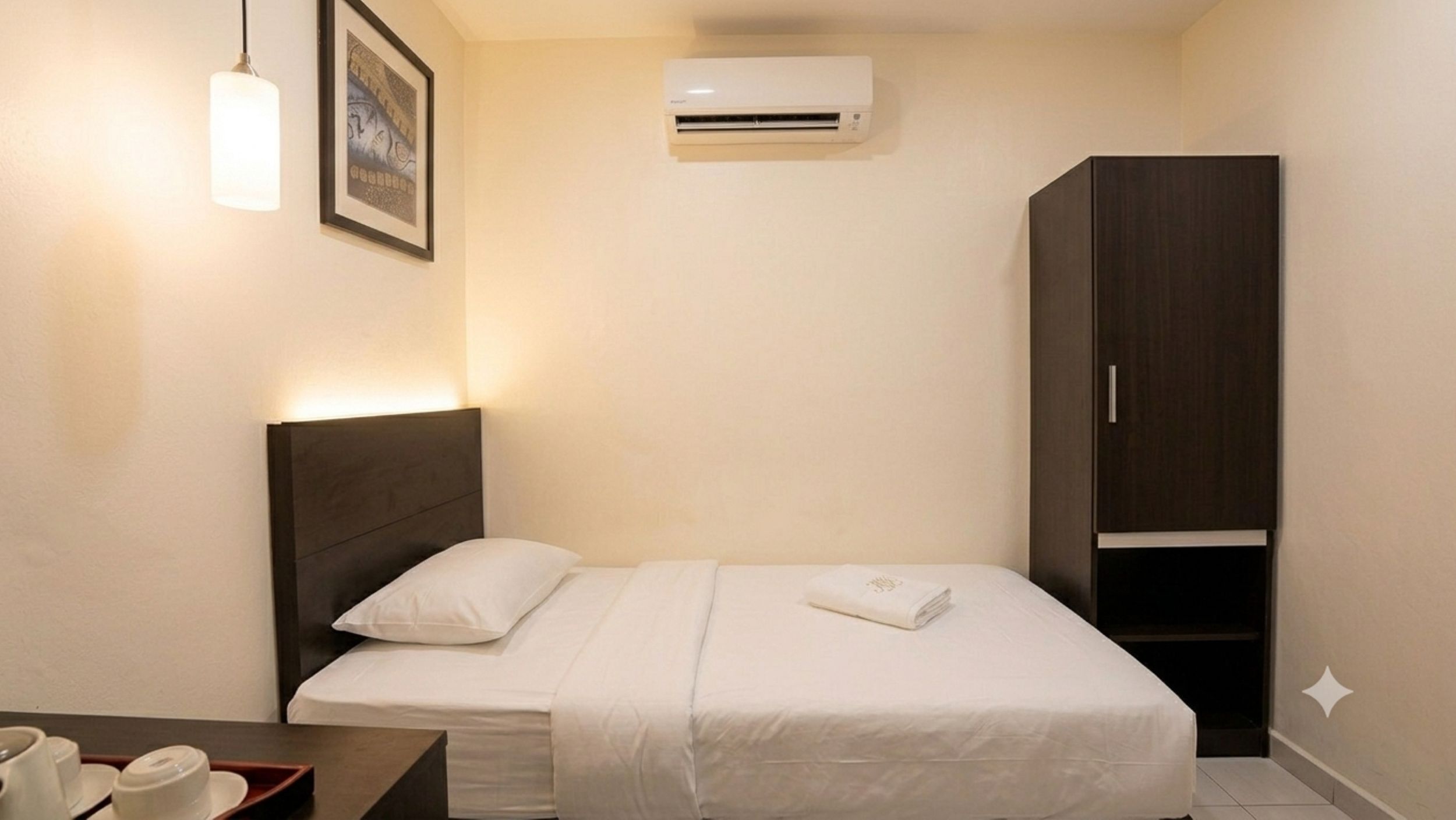 A hotel room with a bed, bedside table, and a wardrobe.