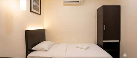 A hotel room with a bed, bedside table, and a wardrobe.