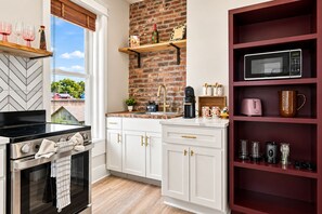 A modern kitchen with white cabinetry, a brick backsplash, and a built-in microwave shelf.