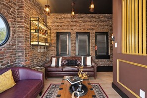A living room with a brick wall, leather sofas, a coffee table, and pendant lighting.