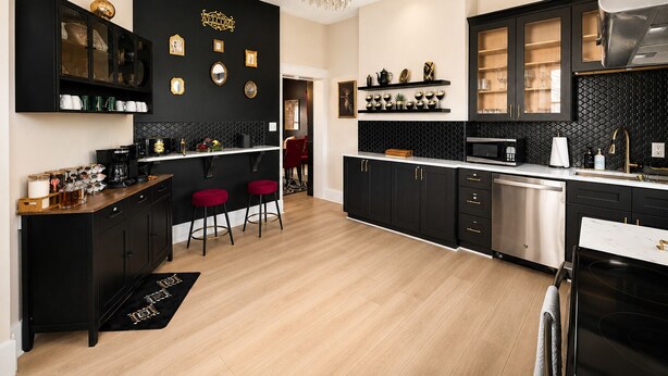 A modern kitchen with black cabinetry, a wooden bar counter, and a chandelier.