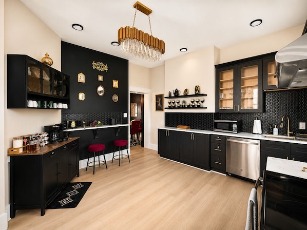 Una cocina moderna con armarios negros, una barra de madera y una araña.
