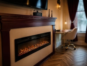 Una chimenea moderna con un televisor encima, un cartel con la palabra 'REMOTE' y un escritorio con una silla al fondo.