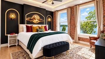 A bedroom with a large bed, a ceiling fan, a view of the outdoors, and a nightstand with decorative items.