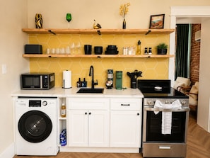 Une cuisine compacte équipée d’un four à micro-ondes, d’un évier, d’une cuisinière et d’un lave-linge.