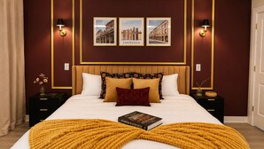 A hotel room with a large bed, a headboard, two nightstands, a book, and framed pictures on the wall.
