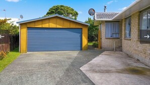 Un garage residenziale con una porta blu, adiacente a una casa in mattoni con un'antenna parabolica e un camino.