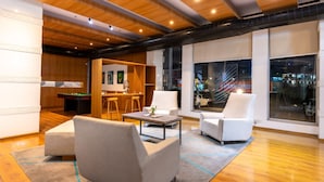 Un área de estar moderna con mesa de billar, bar y asientos cómodos.