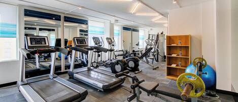 Uma academia moderna com várias esteiras, elípticos e equipamentos de musculação.