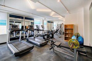 Een moderne sportschool met diverse loopbanden, elliptische trainers en gewichthefapparatuur.