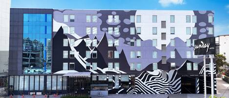 A modern hotel with a unique architectural design featuring geometric patterns and a large reflective glass facade.