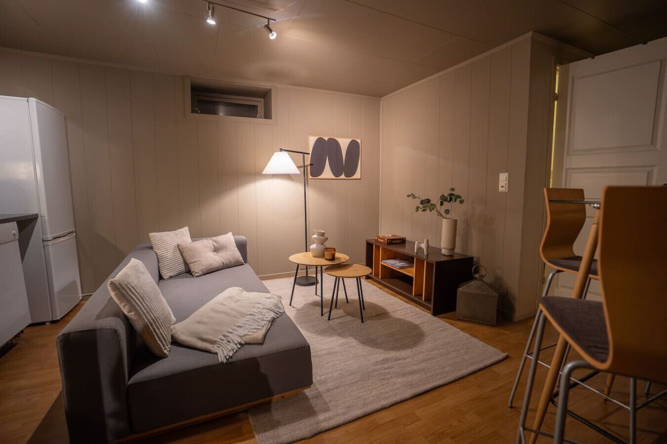 A compact living space with a sofa, a small round table, a lamp, a bookshelf, and a chair.