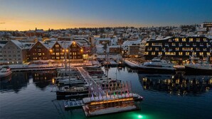 Un port de plaisance avec des bateaux amarrés et des bâtiments dont les fenêtres sont illuminées.