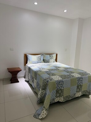 Un dormitorio con una cama, una mesita de noche de madera y una mesilla.