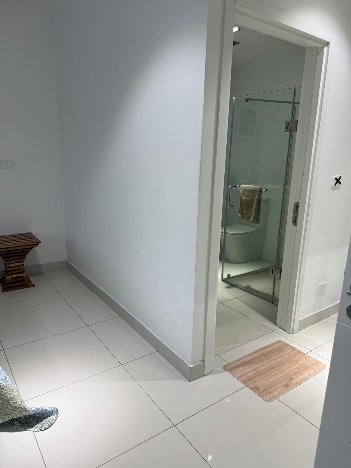 Une salle de bain moderne avec une douche à l’italienne en verre, un banc en bois et un sol carrelé.