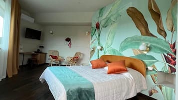 A hotel room with a bed, a desk, chairs, and a large wall mural.