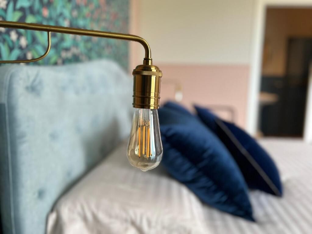 A bed with a headboard, a hanging light fixture, and a pillow.