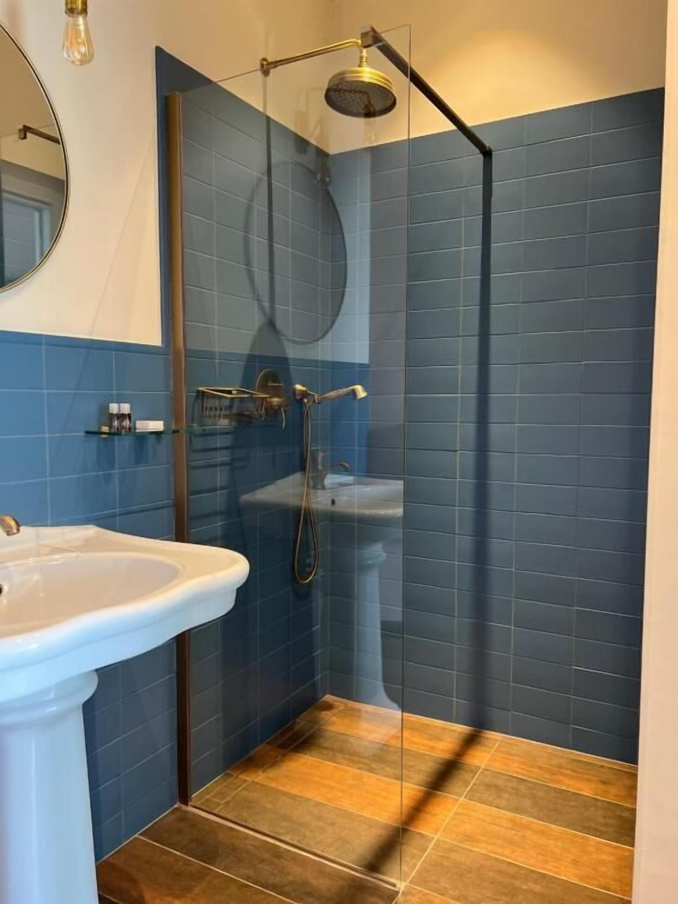 Un baño con ducha, lavamanos y espejo.