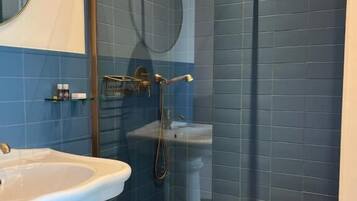 Un baño con ducha, lavamanos y espejo.