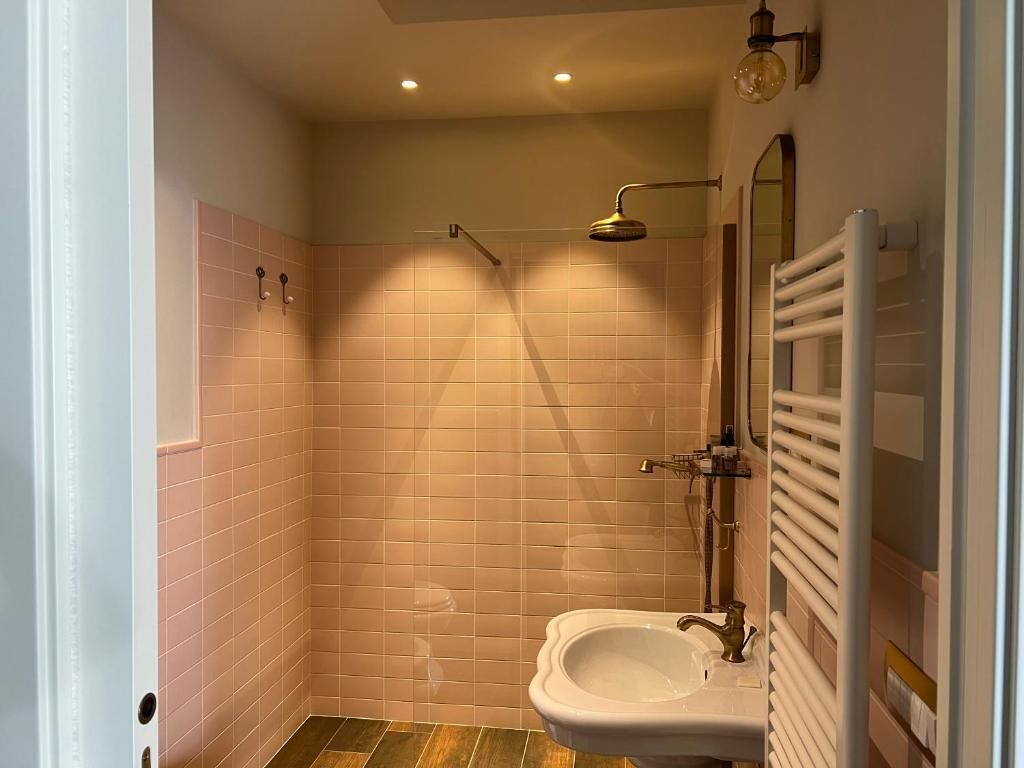 A bathroom with a shower, a sink, and a towel rack.