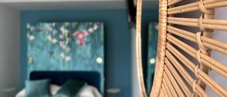 Una habitación con cama, televisor de pared y silla de mimbre.