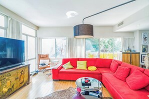 Una sala de estar moderna con un sofá rojo, una televisión y una mesita de centro.