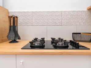 A kitchen with a black stove top, a wooden countertop, and a backsplash with a geometric pattern. - Vivelorural casa Priya, pool and views (Teror)