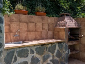 An outdoor kitchen with a stone countertop, a sink, and a pizza oven. - Vivelorural casa Priya, pool and views (Teror)