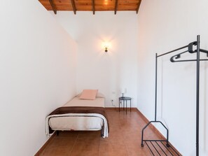 A bedroom with a bed, a hanging light, a small table, and a metal rack. - Vivelorural casa Priya, pool and views (Teror)