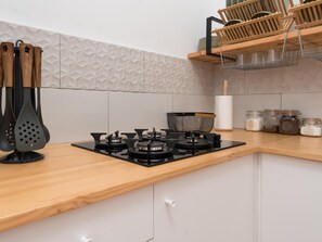 A kitchen with a gas stove, wooden utensils, a spice rack, and a hanging rack. - Vivelorural casa Priya, pool and views (Teror)