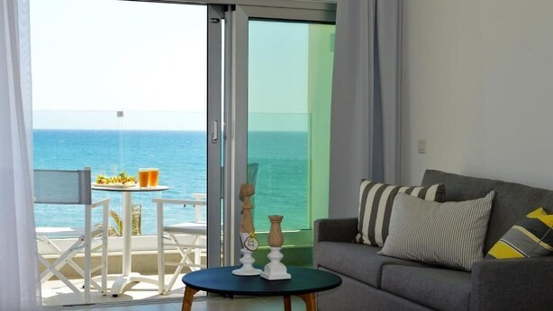 A room with a balcony, a sofa, a small table, and a bed.