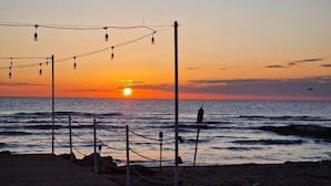 A sunset view from a beachside location with a wooden deck and string lights.