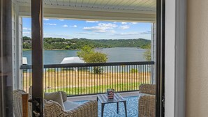 Ein Balkon mit Korbmöbeln, Blick auf einen See und eine entfernte Uferlinie.