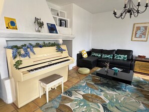 A living room with a piano, a black sofa, a coffee table, and a patterned rug.