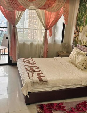 A bedroom with a bed, curtains, a nightstand, and a chair. - ManilaBay Home condo
offers you 2 bedrooms with balcony, gym, swimming pool. (Manila)
